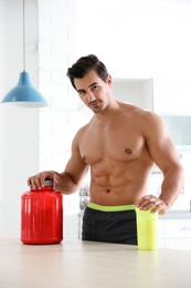 Photo of Young shirtless athletic man with protein shake powder in kitchen