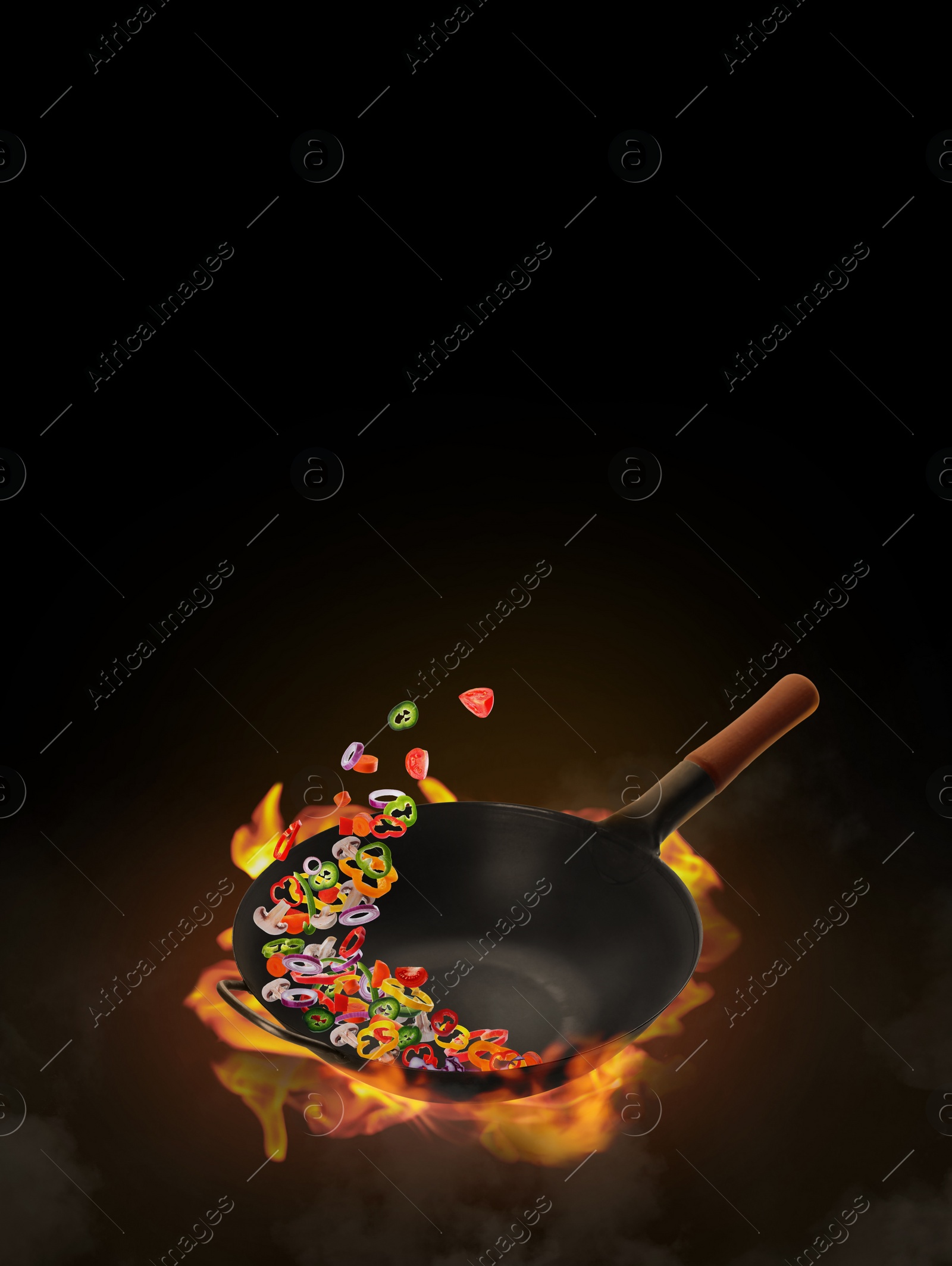 Image of Wok with tasty ingredients and fire on black background