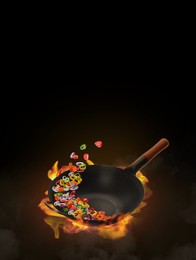 Image of Wok with tasty ingredients and fire on black background