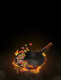 Wok with tasty ingredients and fire on black background