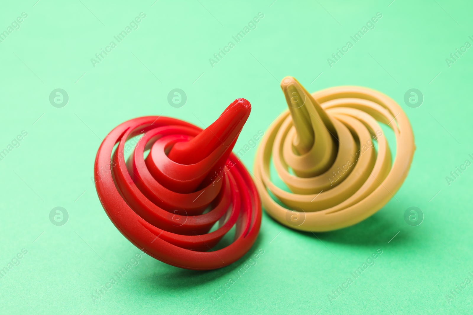 Photo of Two colorful spinning tops on green background, closeup