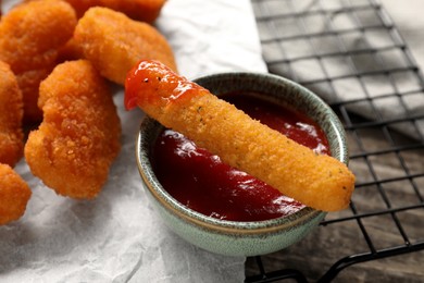 Photo of Tasty chicken nuggets, cheese stick and ketchup on table, closeup