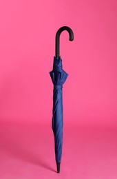 Photo of Stylish closed blue umbrella on pink background