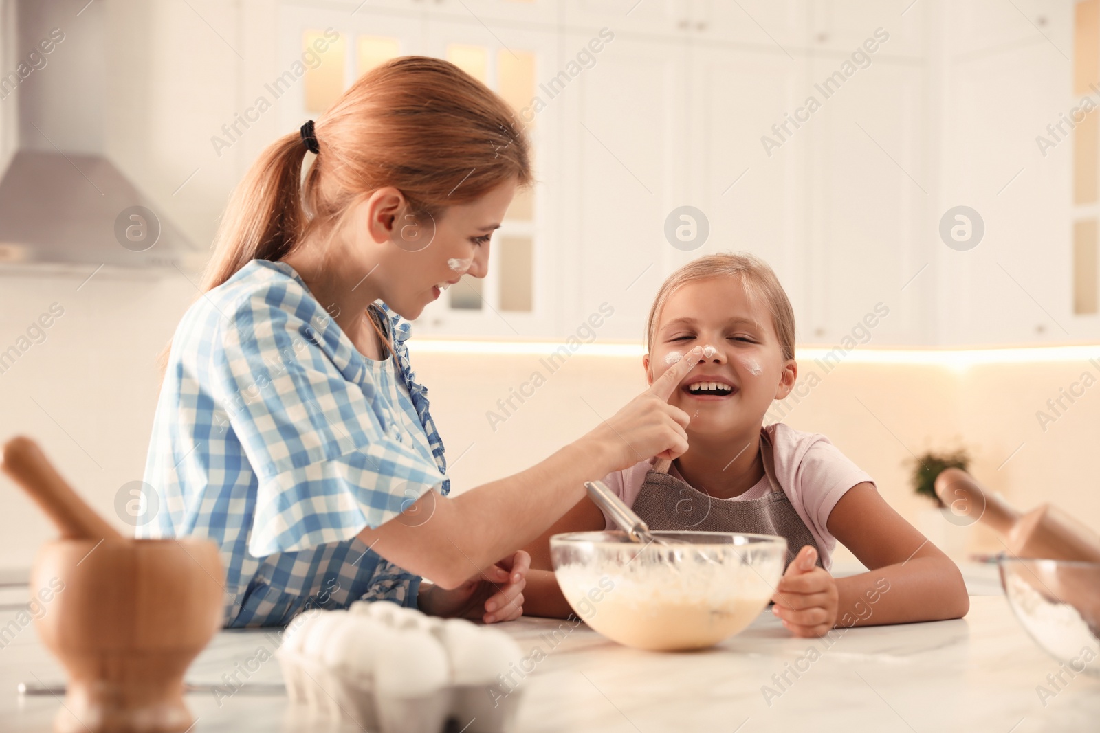 Photo of Mother and daughter making dough together in kitchen