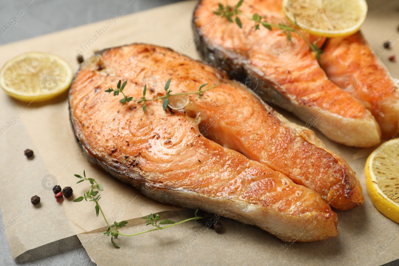 Photo of Delicious roasted fish with thyme and lemon on parchment paper, closeup