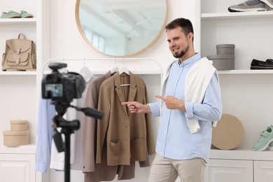 Smiling fashion blogger showing clothes while recording video at home