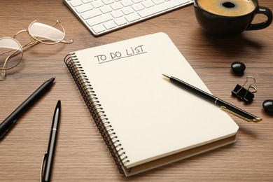 Photo of Notepad with inscription To Do List, pens, glasses and cup of coffee on wooden table