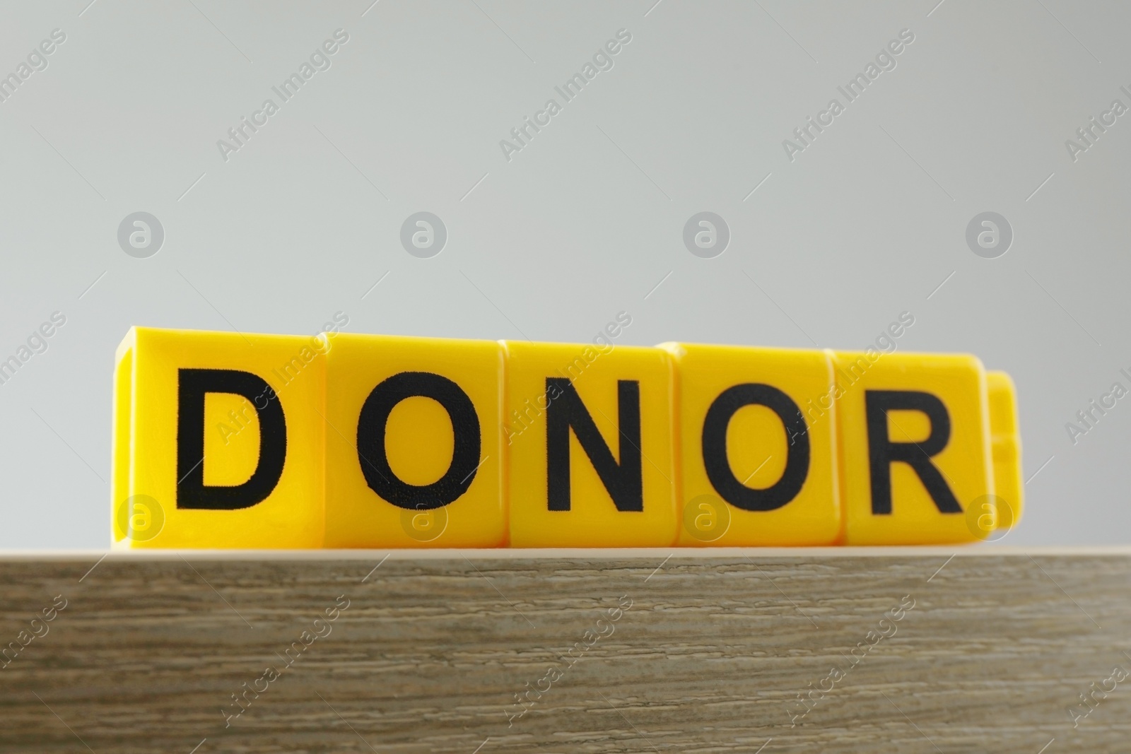 Photo of Word Donor made of yellow cubes on wooden table, closeup