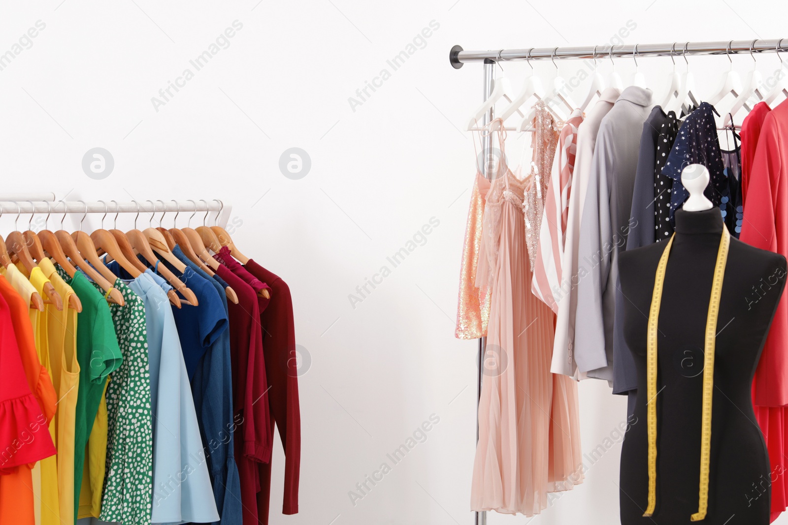 Photo of Racks with collection of trendy clothes on white background. Stylist's workplace