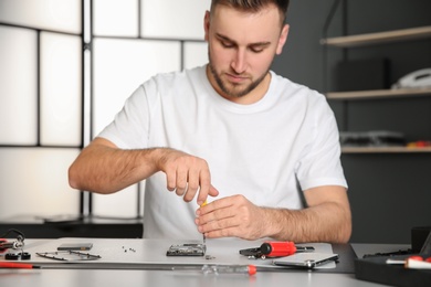 Technician repairing mobile phone at table in workshop