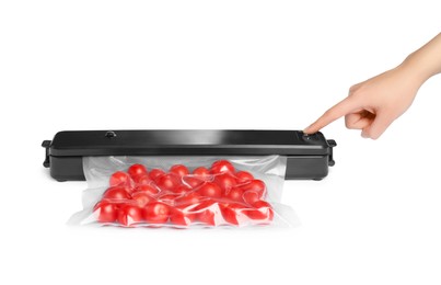 Photo of Woman using button on sealer for vacuum packing with plastic bag of cherry tomatoes on white background, closeup