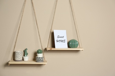 Wooden shelves with different decorative elements on beige wall