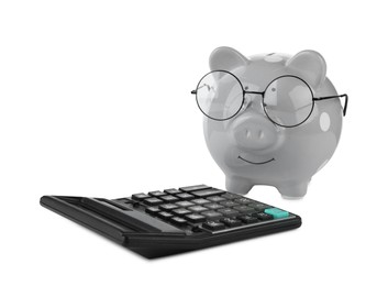 Photo of Calculator and grey piggy bank in glasses isolated on white