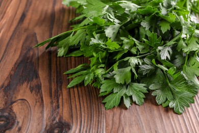 Photo of Bunch of fresh green parsley leaves on wooden table, closeup