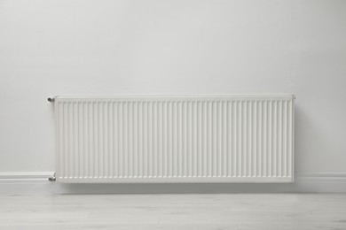 Photo of Modern radiator on white wall indoors. Central heating system