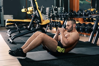 Strong man doing crunches on mat in gym