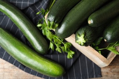 Crate with green zucchinis and parsley on table, flat lay