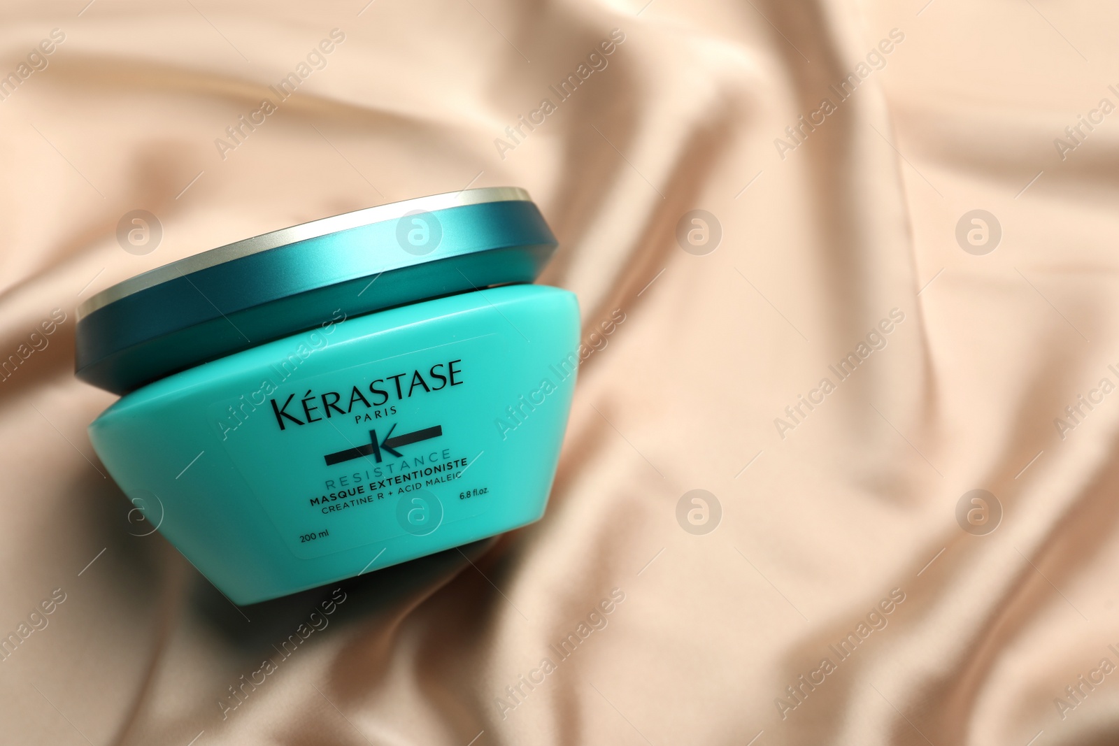 Photo of MYKOLAIV, UKRAINE - SEPTEMBER 07, 2021: Kerastase hair care mask on silk fabric, top view. Space for text