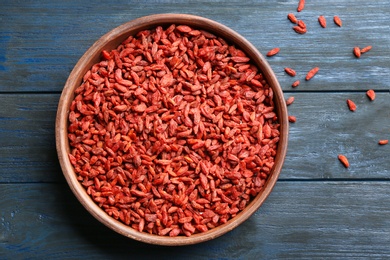 Photo of Bowl of dried goji berries on wooden table, top view. Healthy superfood