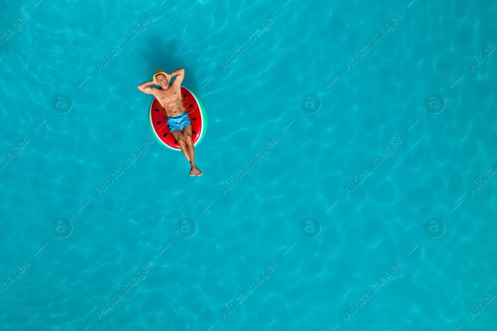 Image of Happy man with inflatable ring in swimming pool, top view and space for text. Summer vacation