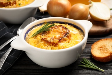 Photo of Tasty homemade french onion soup served on black wooden table