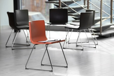 Photo of Red chair with clipboard in office prepared for group therapy. Meeting room interior