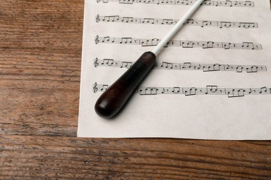 Photo of Conductor's baton and sheet music on wooden table, above view