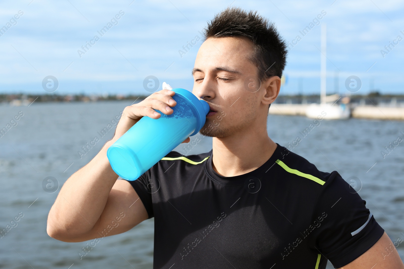 Photo of Young man drinking protein shake near river