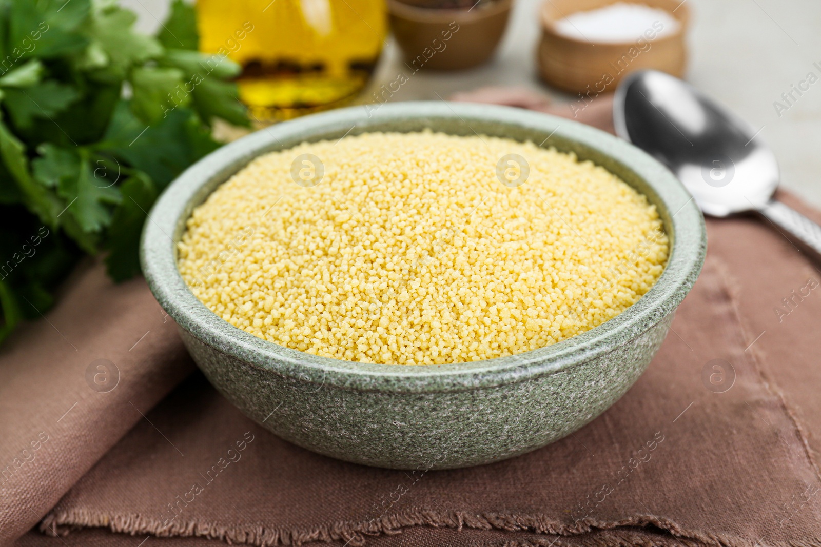 Photo of Bowl of raw couscous on table, closeup