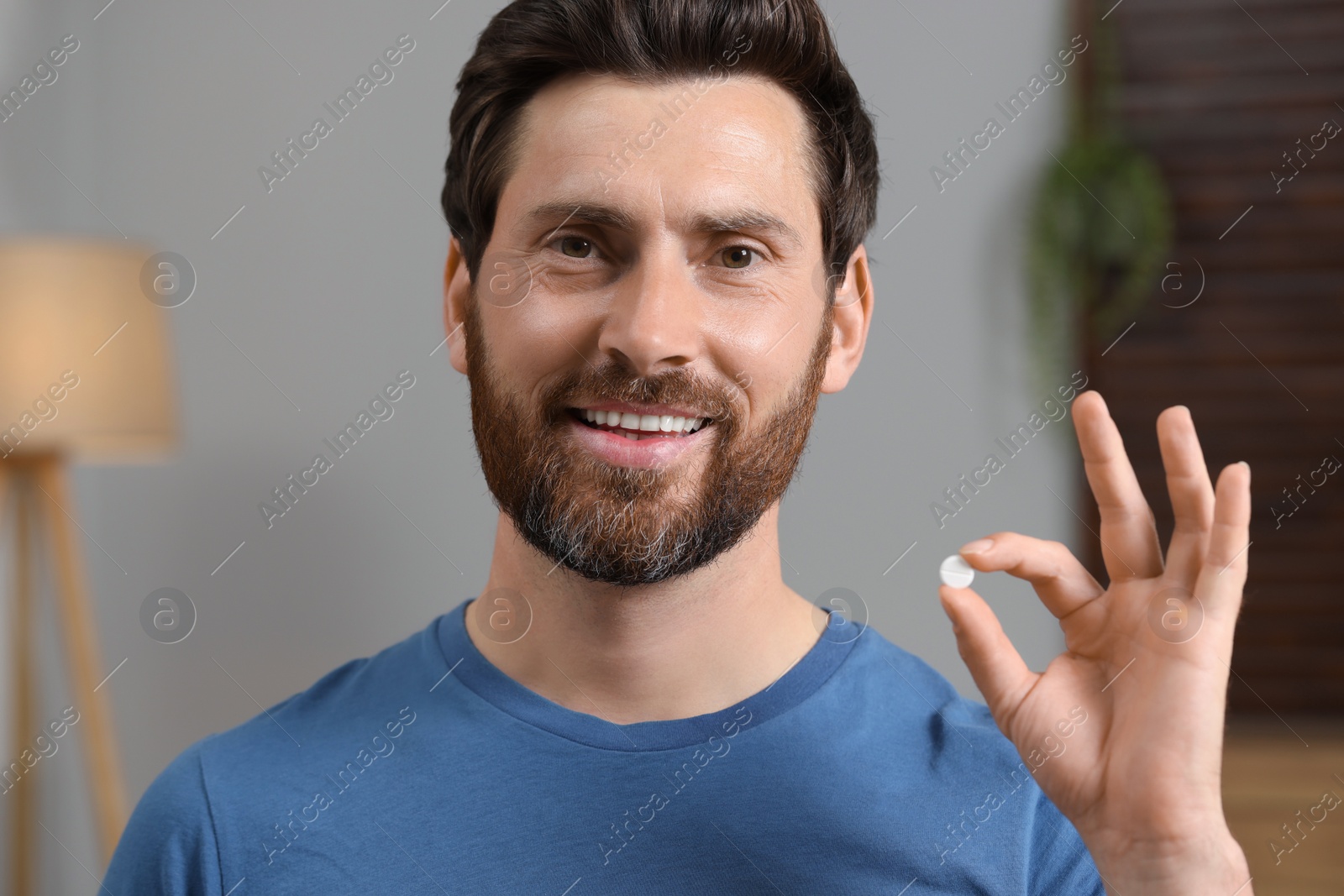 Photo of Portrait of happy man with pill at home