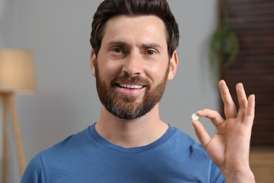 Portrait of happy man with pill at home