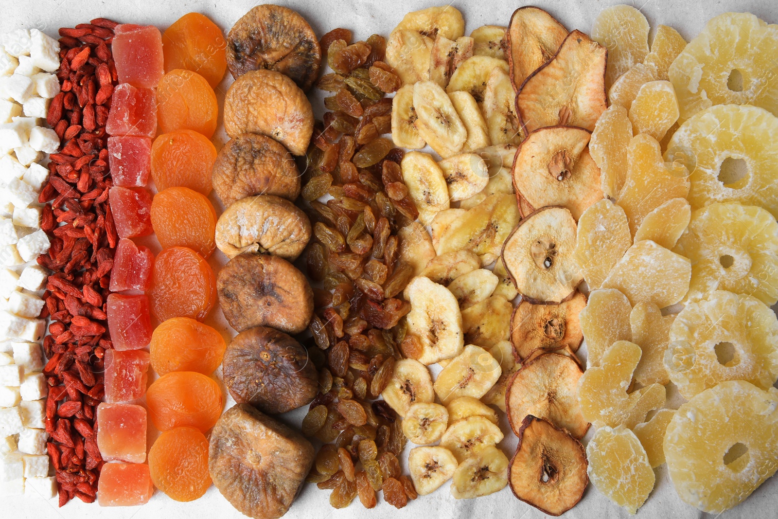 Photo of Different tasty dried fruits on paper, flat lay