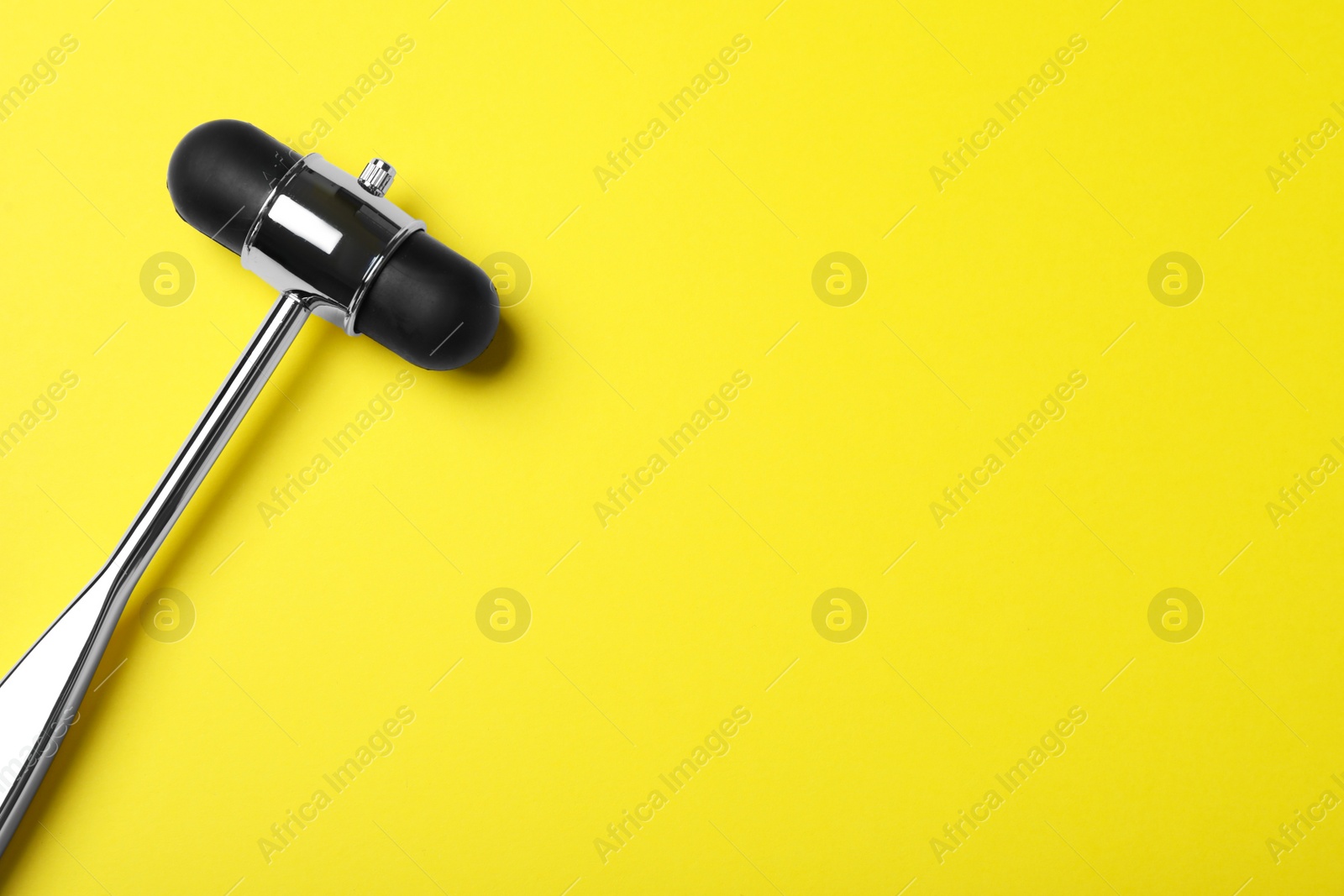 Photo of Reflex hammer on yellow background, top view with space for text. Nervous system diagnostic