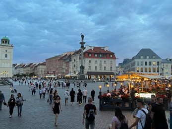Photo of WARSAW, POLAND - JULY 15, 2022: View of crowded Old Town Market Place under cloudy sky in evening