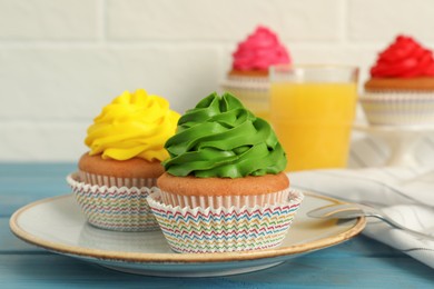 Photo of Delicious cupcakes with colorful cream on light blue wooden table