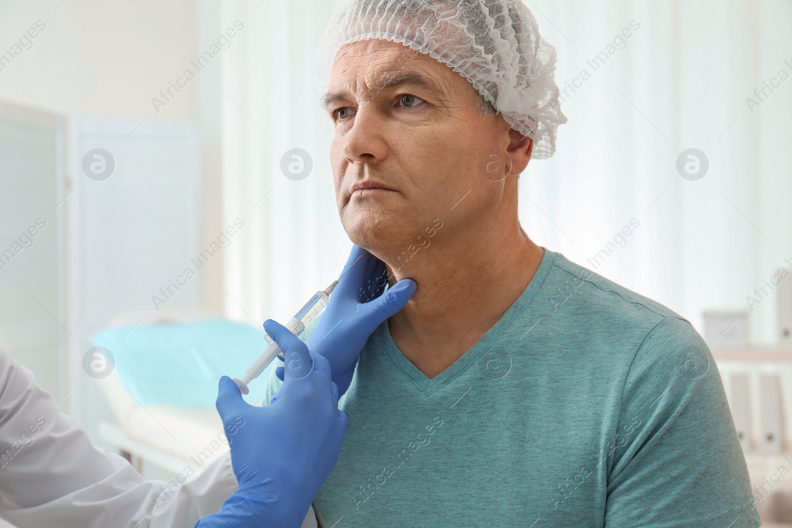 Photo of Mature man with double chin receiving injection in clinic