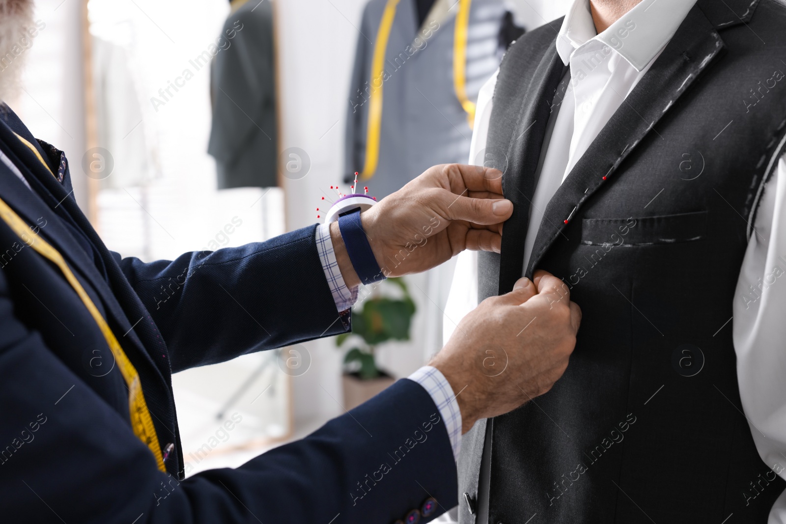 Photo of Professional tailor working with client in atelier, closeup