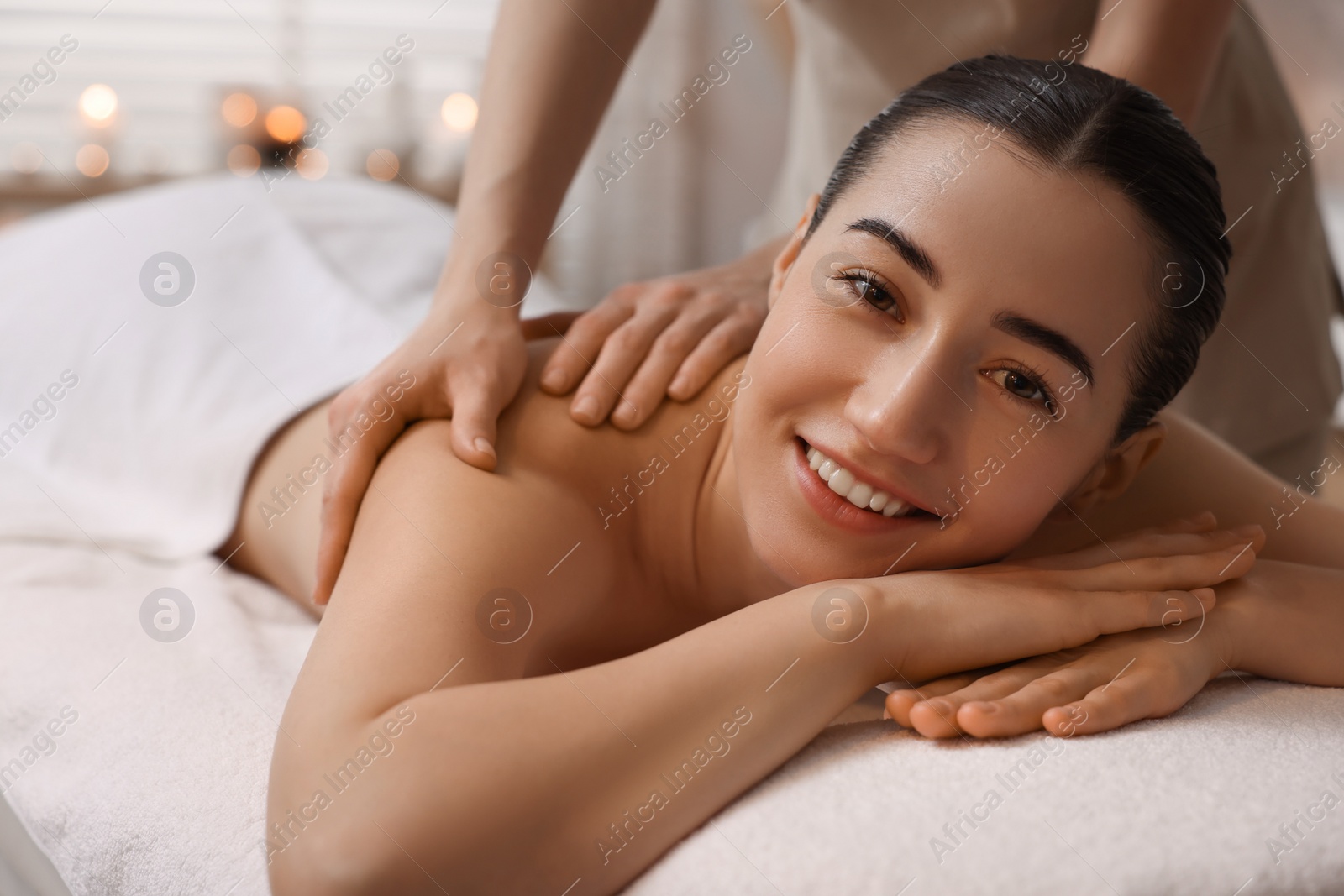 Photo of Woman receiving back massage on couch in spa salon