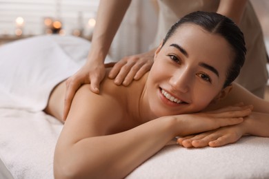 Photo of Woman receiving back massage on couch in spa salon