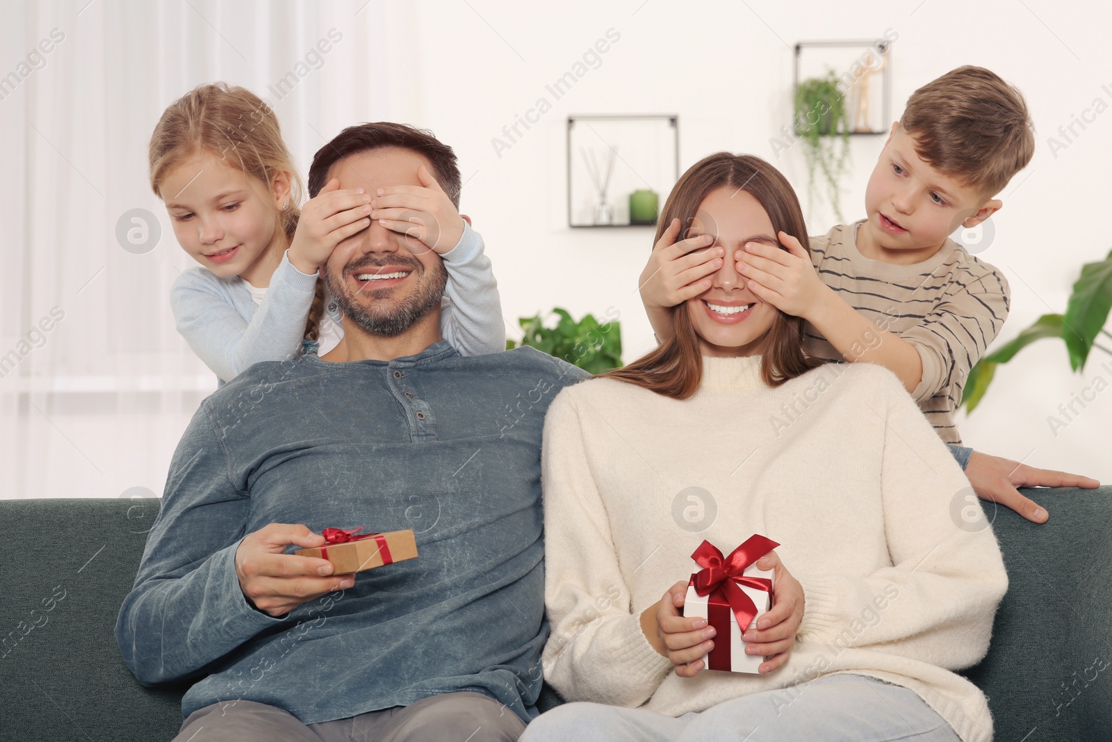 Photo of Little children presenting their parents with gifts at home
