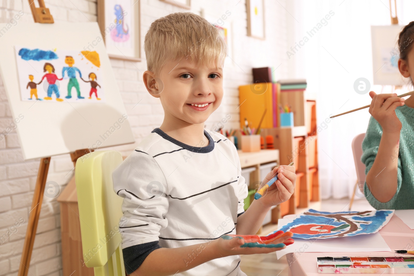 Photo of Cute little child painting his palm at table in room