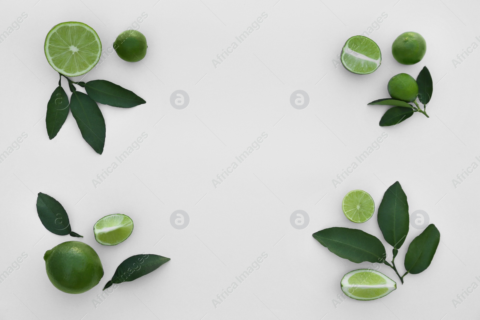 Photo of Whole and cut fresh limes with leaves on white background, flat lay. Space for text