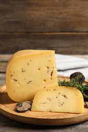 Photo of Delicious cheese, fresh black truffles and thyme on wooden table