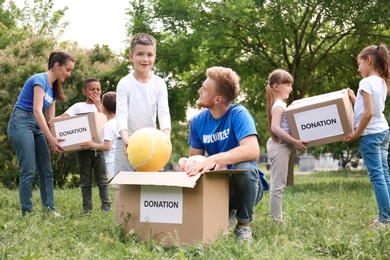 Photo of Volunteers and kids with donation boxes in park