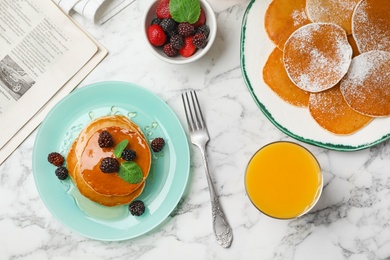 Photo of Delicious pancakes with berries, honey and glass of juice served for breakfast on table, top view