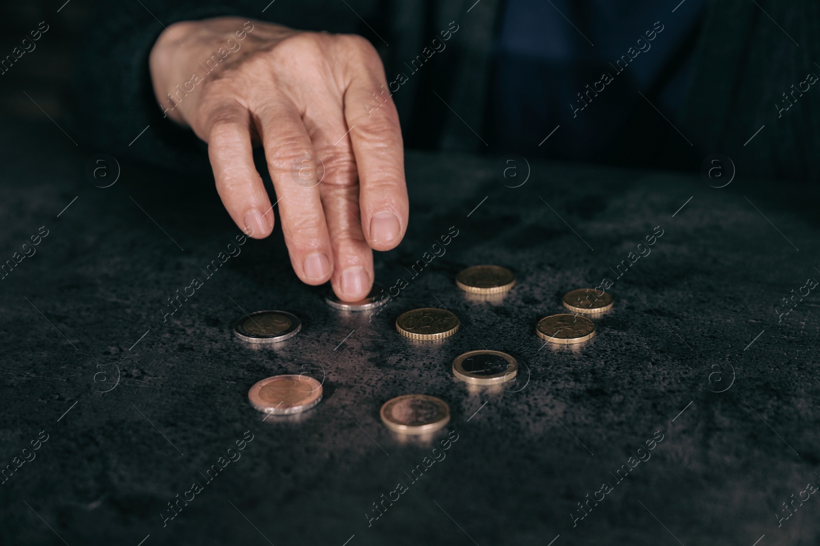 Photo of Poor mature woman counting coins at table, closeup