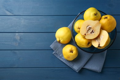 Photo of Tasty ripe quinces in bowl on blue wooden table, top view. Space for text