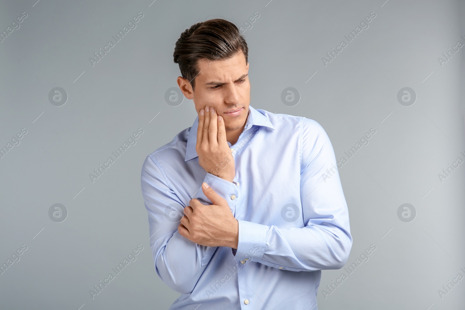 Photo of Young man suffering from toothache on grey background