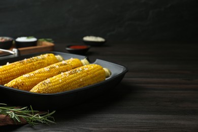 Grill pan with tasty frying corn on dark grey wooden table. Space for text