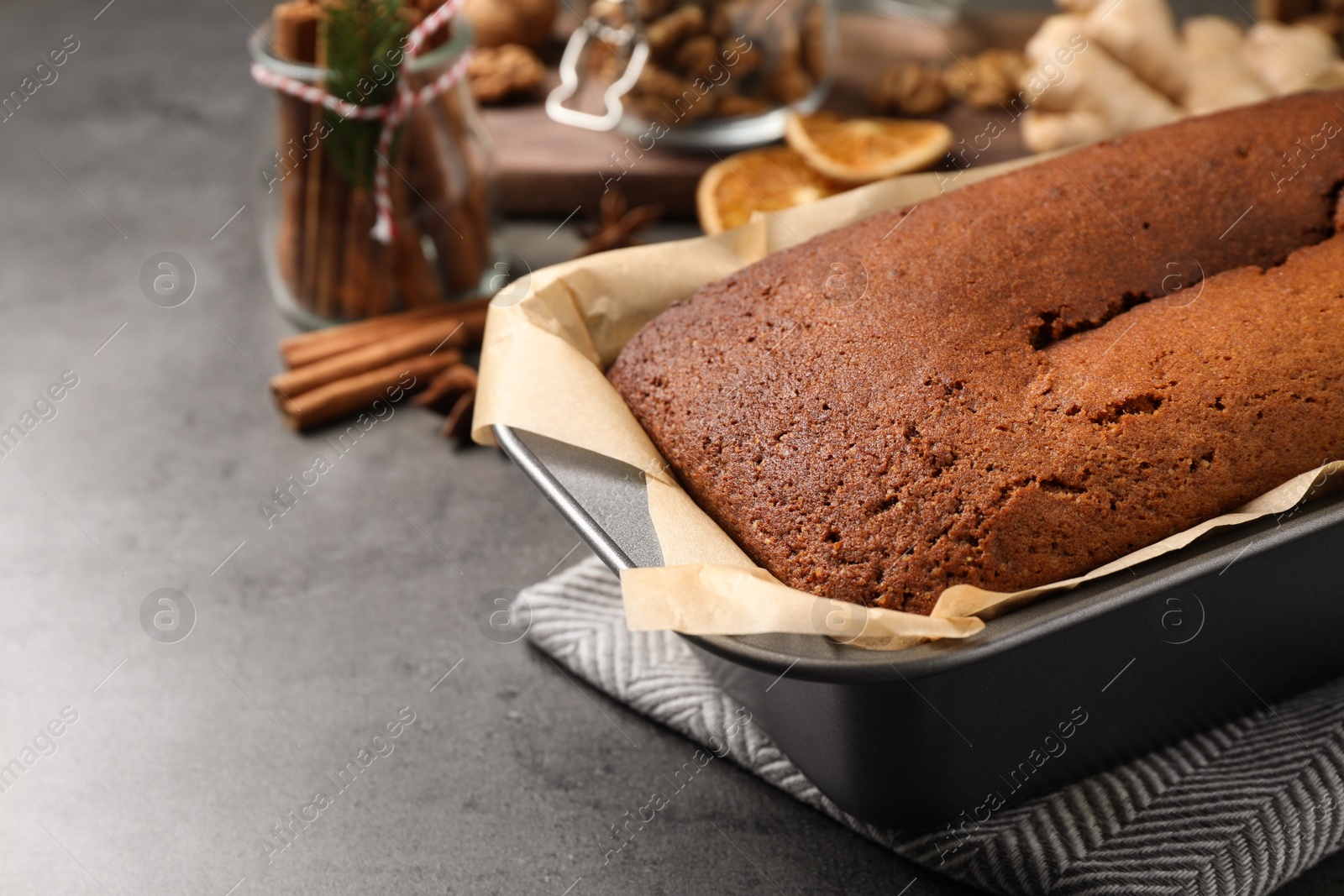 Photo of Delicious gingerbread cake in baking dish on grey table, space for text